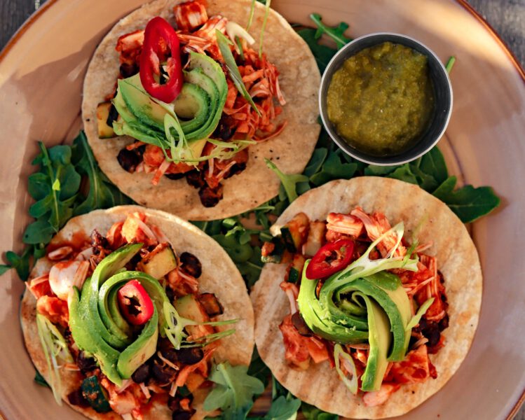 Plate of 3 tortillas topped with grilled jackfruit and bright green avocado arranged in a circular motion
