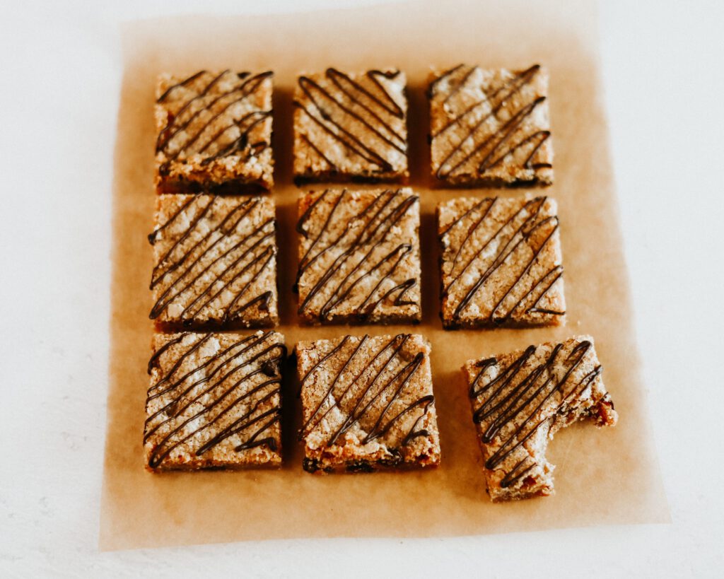 9 cookie bars drizzled in chocolate, cut into squares with bite taken out of one