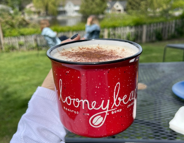 Red mug labeled 'looney bean' held at a park in bend oregon