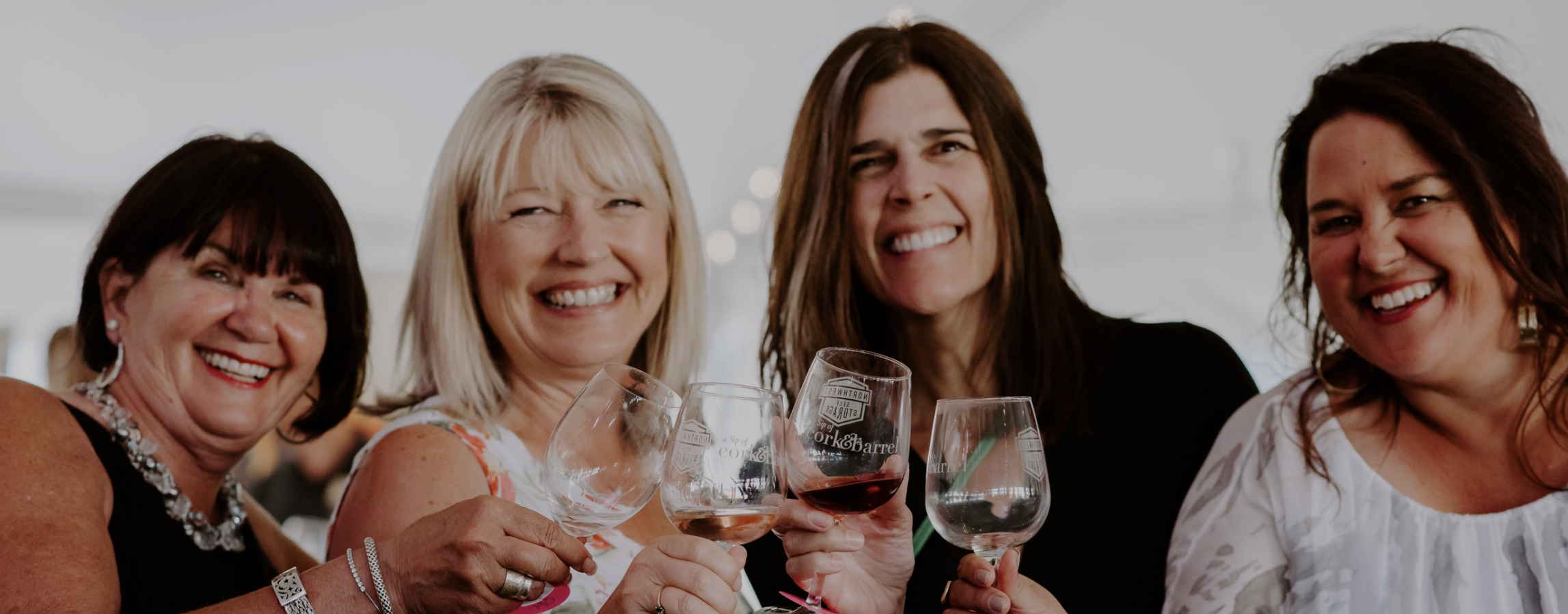 group of four women cheers wine glasses at cork and barrel grand cru evening bend oregon