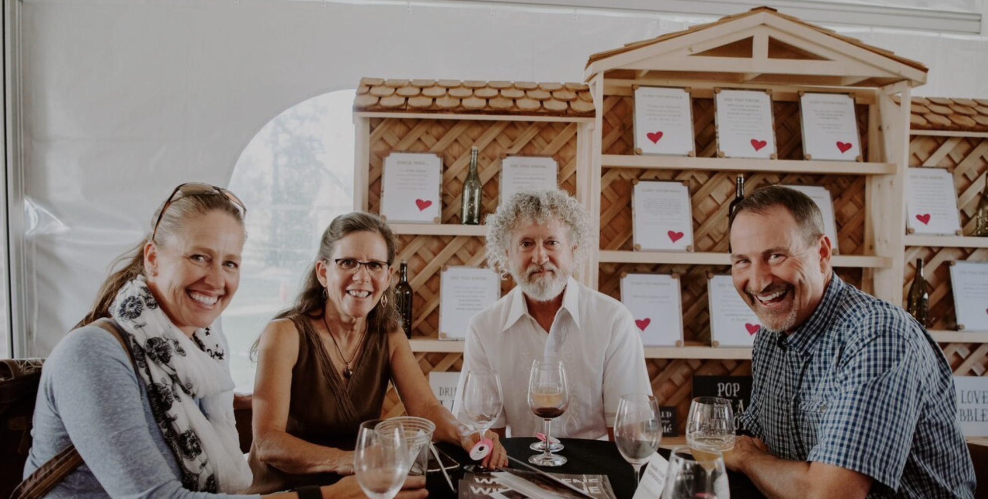 group of men and women sit at a table holding glasses of red wine for bend oregon cork and barrel