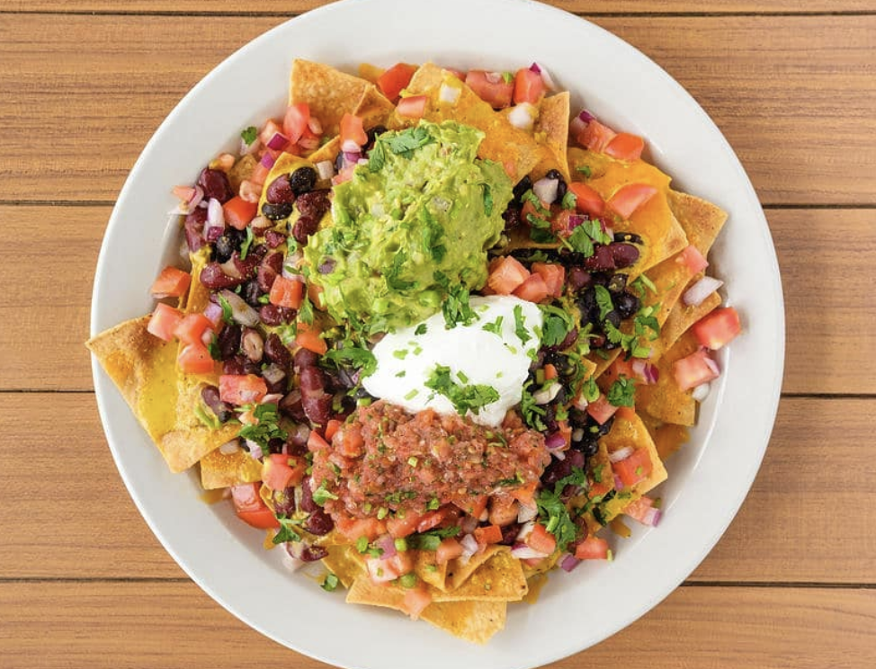 Plate of nachos topped with beans, diced tomato, sour cream, guacamole, and cheese at active culture in bend oregon