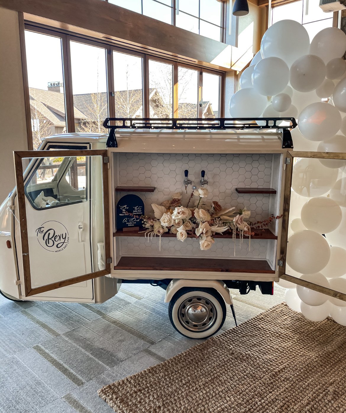 White Vintage Italian cart turned into a mobile bar cart is surrounded by white balloons