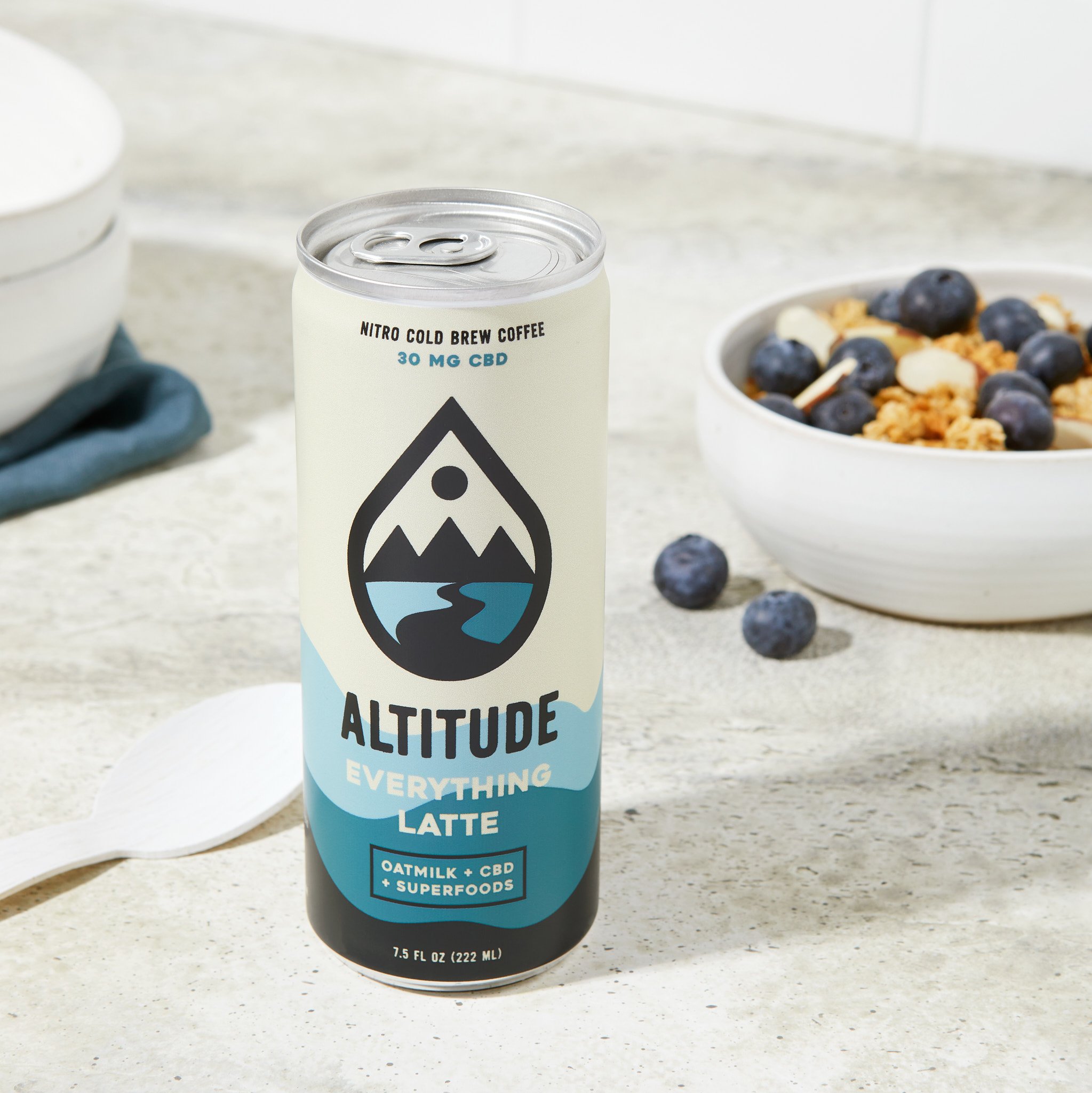 White and blue can of Altitude Beverages coffee reads "Everything Latte" with a bowl of oatmeal in the background