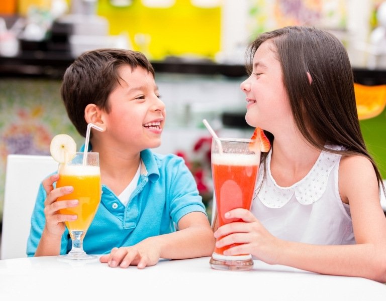 two children smile while drinking soda from a straw on vacation