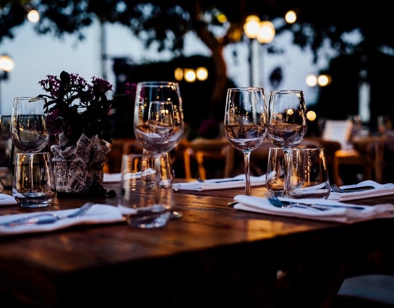 Wine glasses sit on a table at night with twinkling lights in background