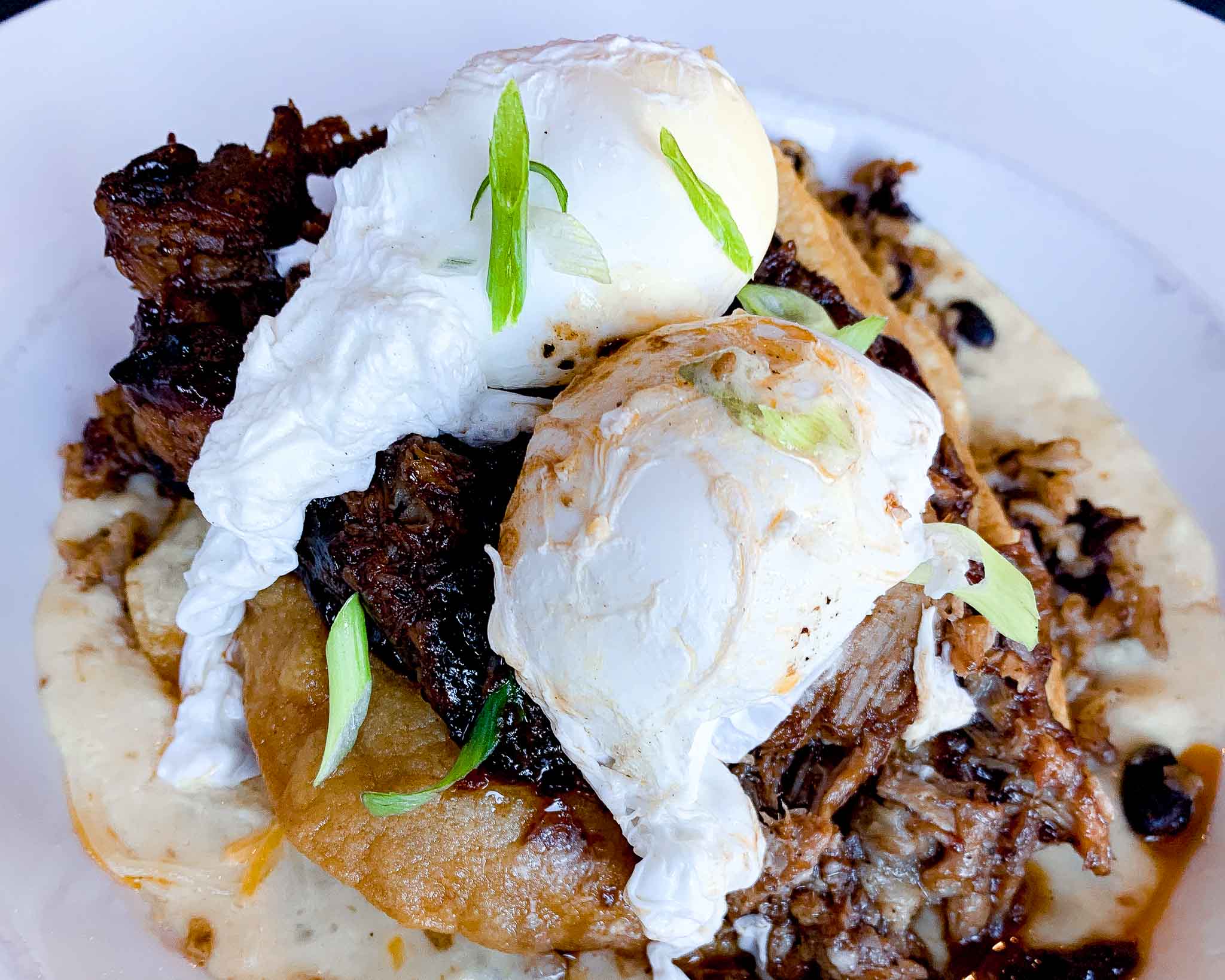 poached eggs sit on top of pulled pork with hollandaise sauce