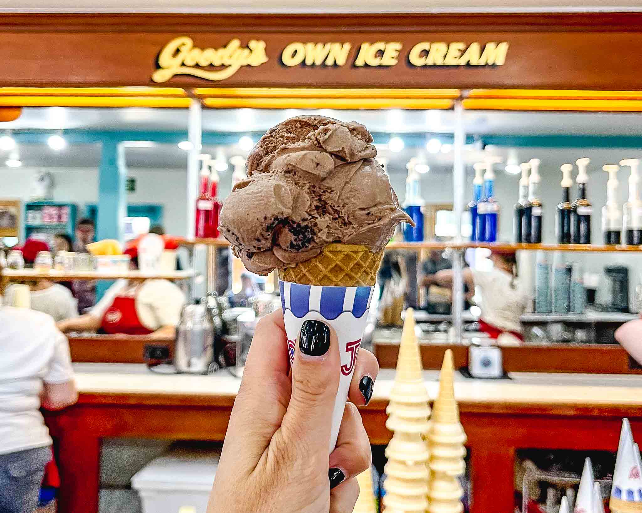 hand holds a cone with scoop of chocolate ice cream