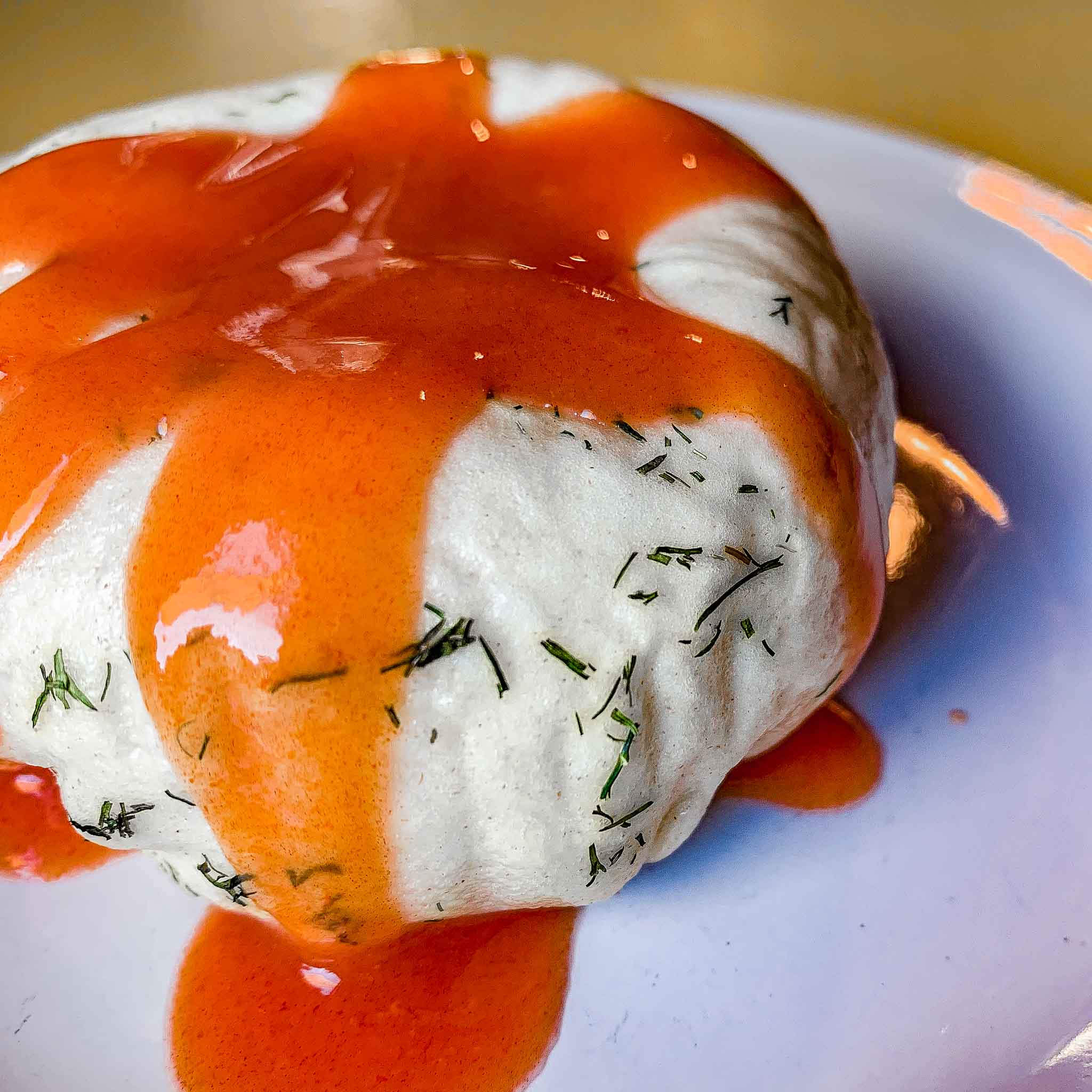 Red hot sauce covers a dumpling rolled in fresh green herbs