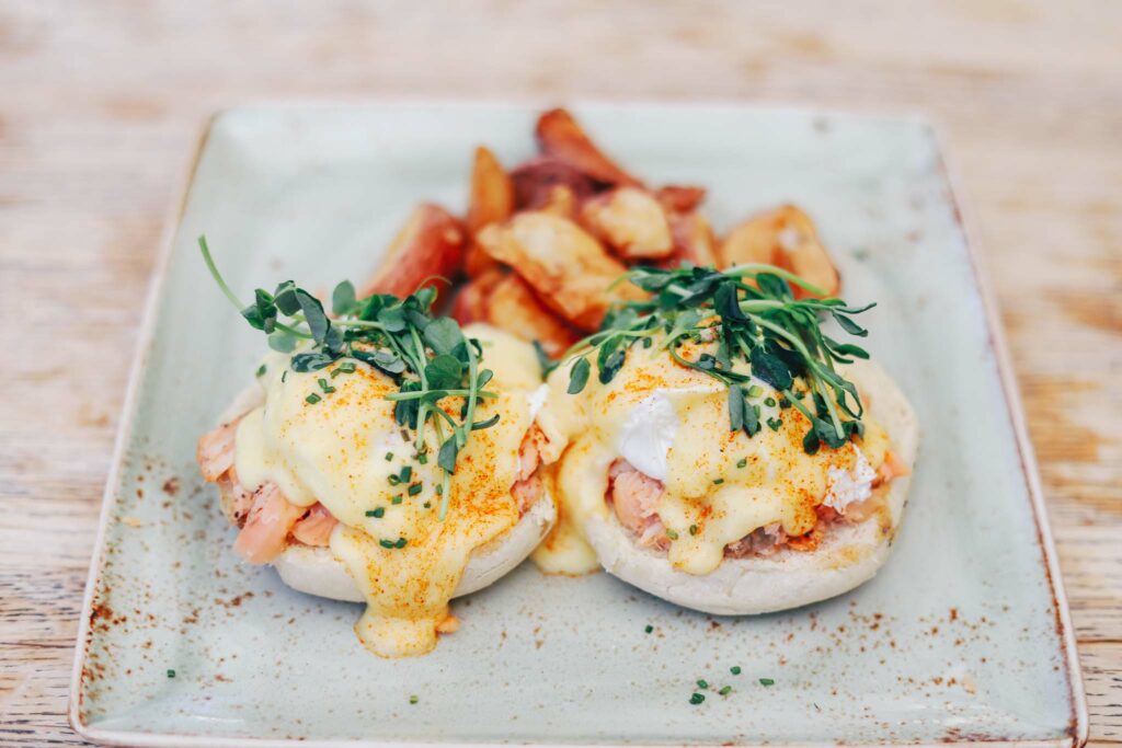 Focus on two eggs benedict topped with salmon and hollandaise sauce dripping down the front of the English muffin