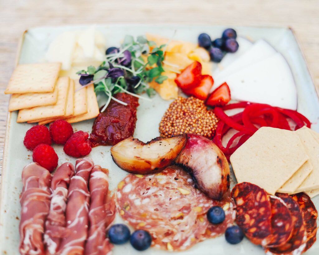 Overhead view of charcuterie platter that features cured meats, slices of cheese, and crackers