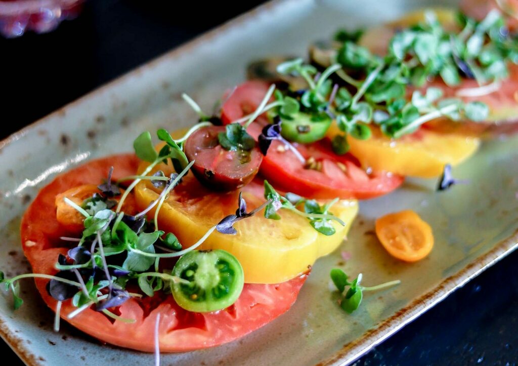 Tri colored tomatoes thickly sliced and topped with basil microgreens
