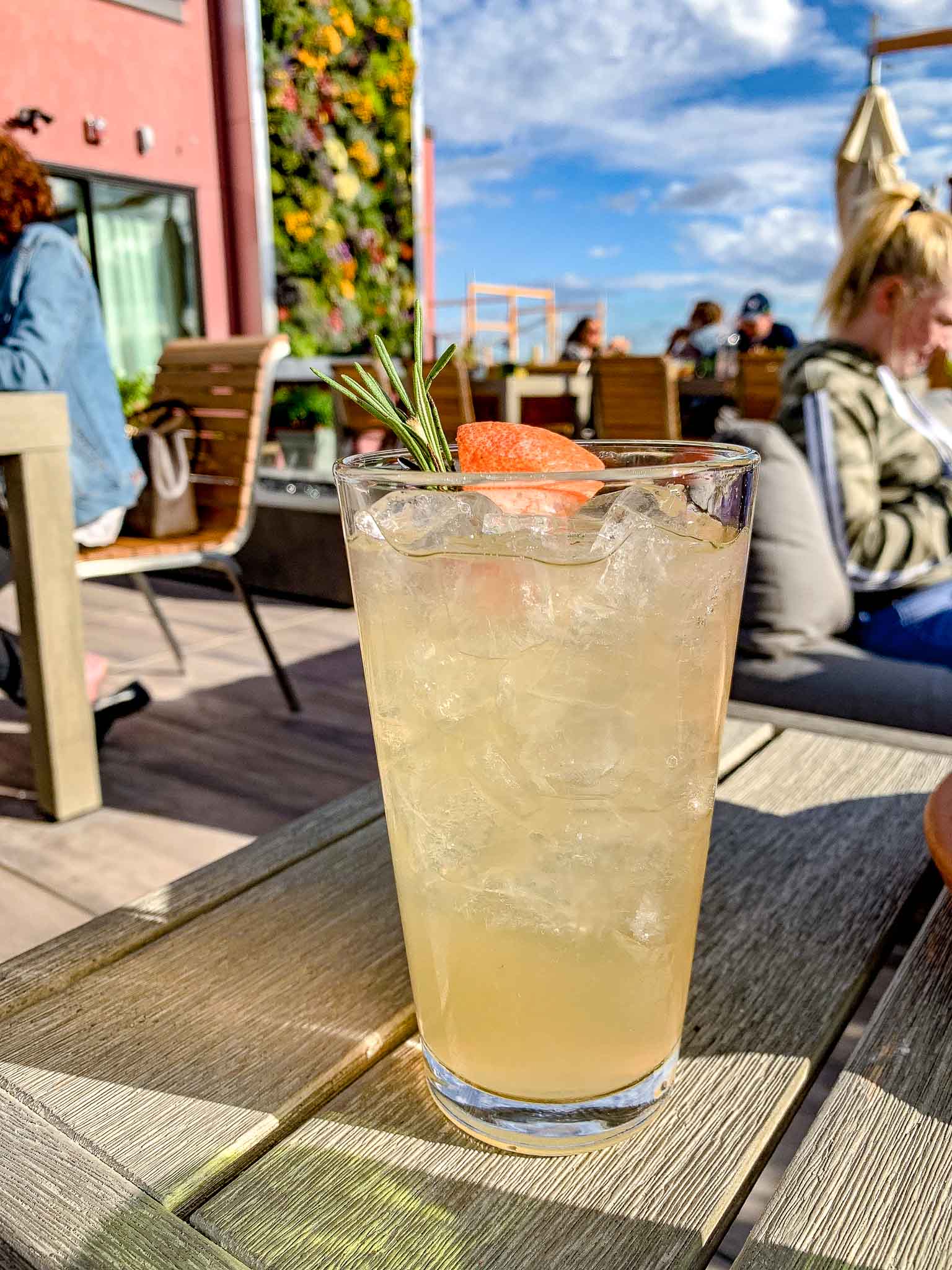 yellow colored cocktail sits in a tall glass with a sprig of rosemary at the rooftop bar in redmond