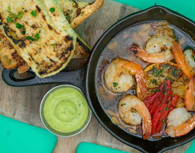 overhead view of grilled bread and shrimp in ajillo sauce