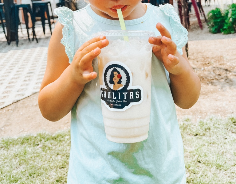 child holds an horchata with a sticker labeled "chulitas"