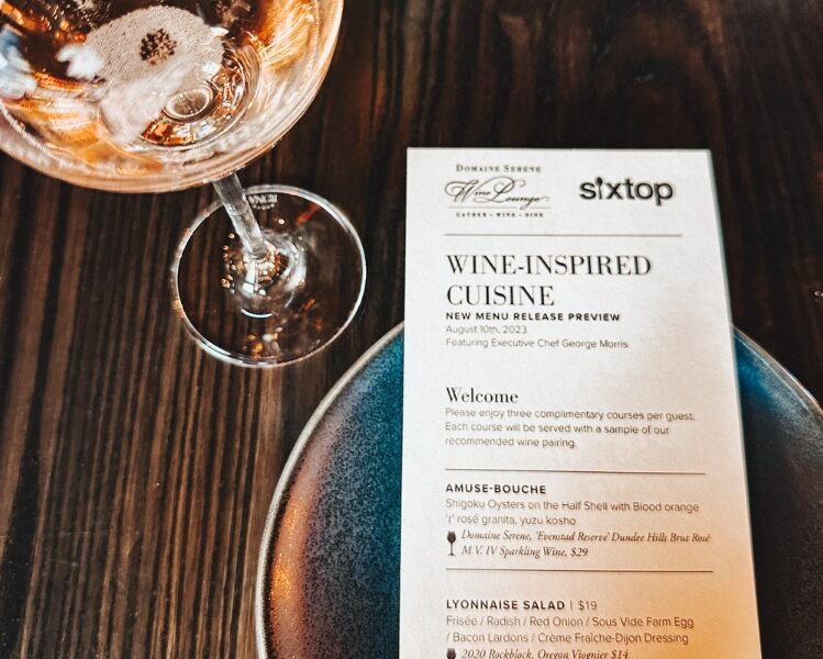glass of sparkling domaine serene wine next to the menu