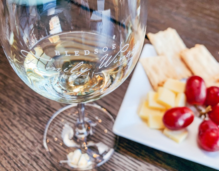 wine glass with white wine next to plate of crackers