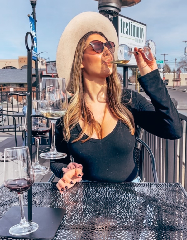 woman takes a sip of champagne from a glass on a patio outside on a wrap around porch
