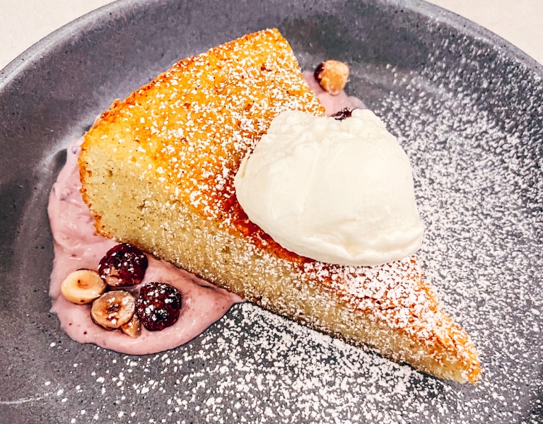 slice of yellow caked topped with gelato and powdered sugar
